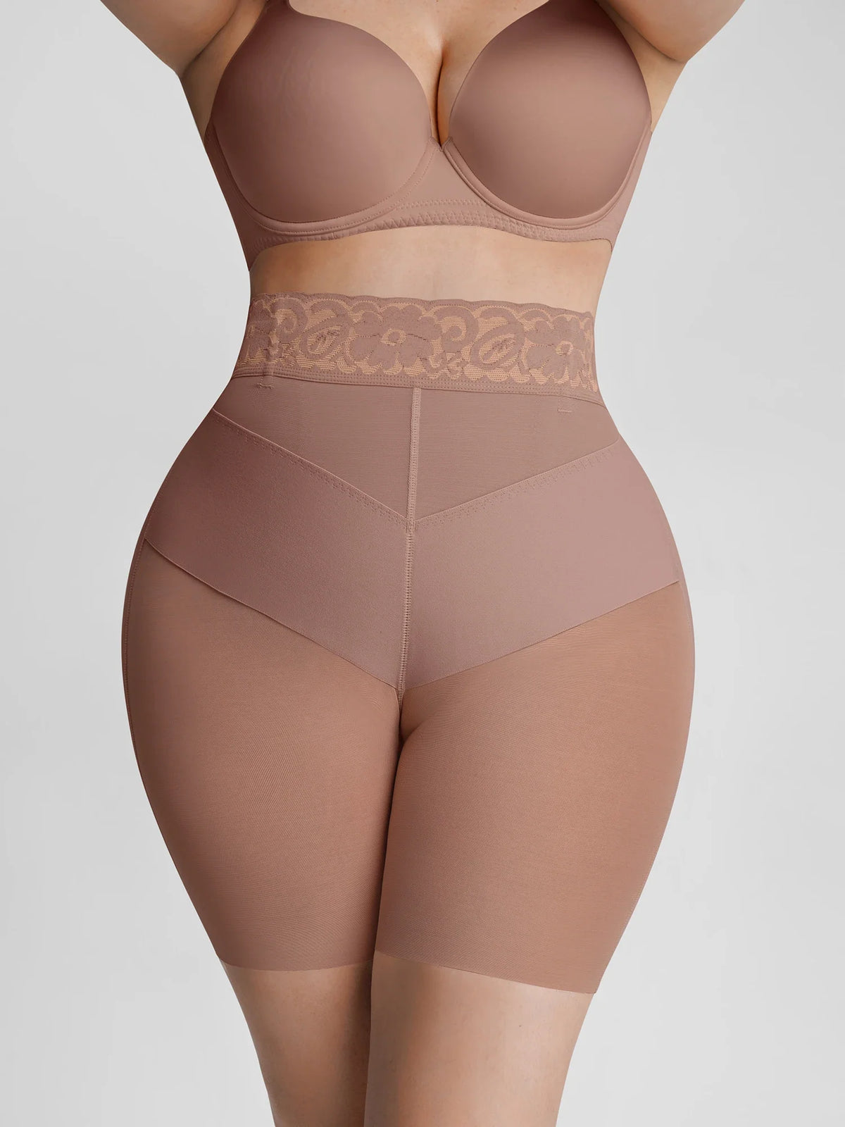 A model wearing a matching nude-beige shapewear set consisting of a high-waisted brief with lace trim and a bra, shown against a light gray studio background.