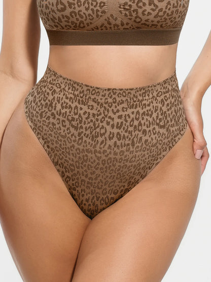 A close-up of a model wearing a brown and beige leopard print high-waisted bikini bottom with a matching bandeau-style top edge visible, against a light gray studio background.