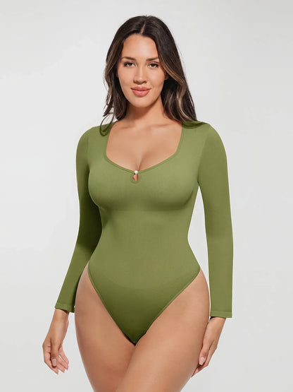 Front view of a model wearing an olive green long-sleeve seamless ribbed bodysuit featuring a low scoop neckline with a pearl button accent