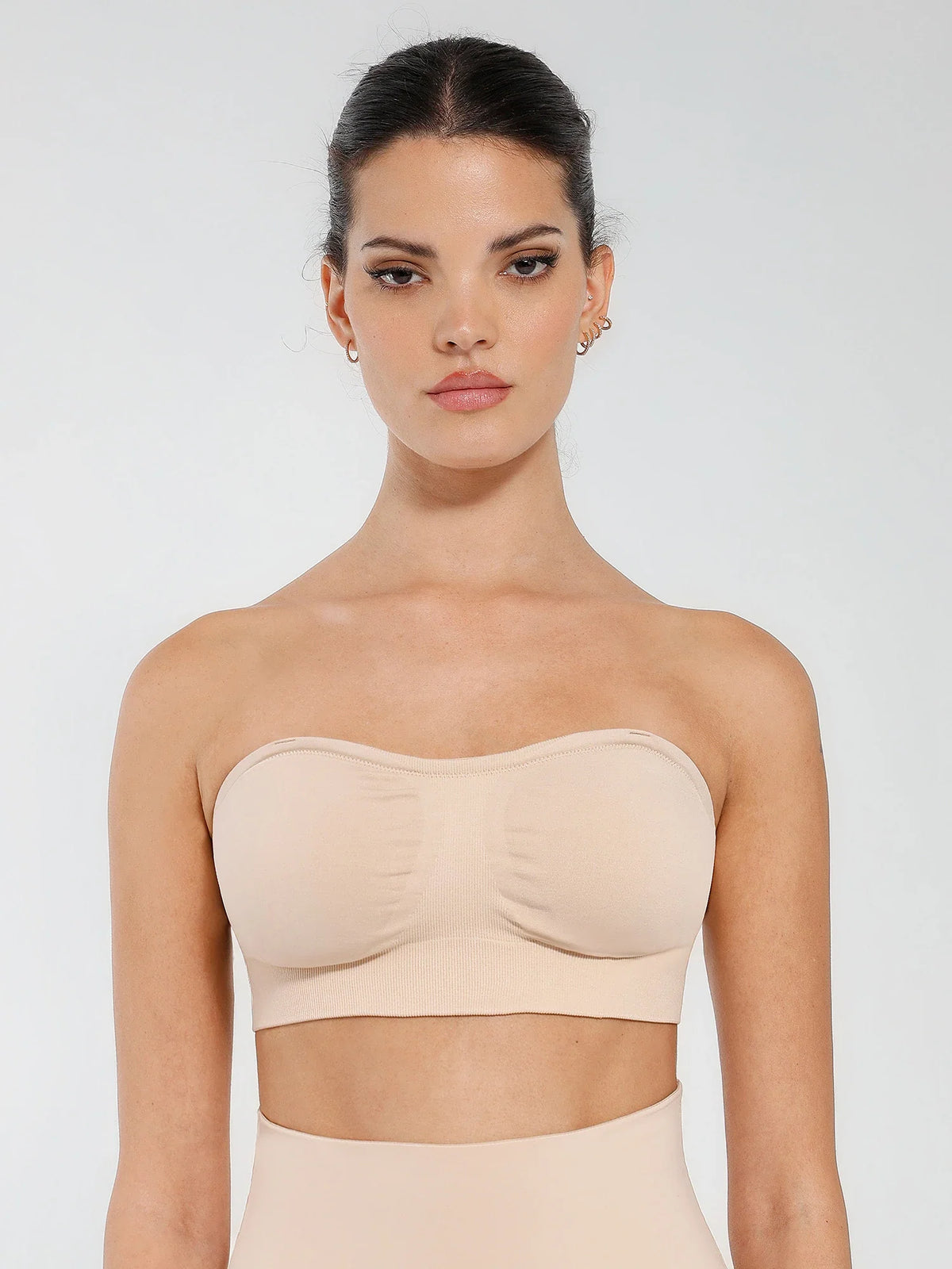 Woman wearing a beige strapless top against a white background