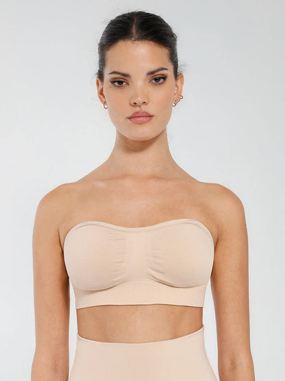 Woman wearing a beige strapless top against a white background