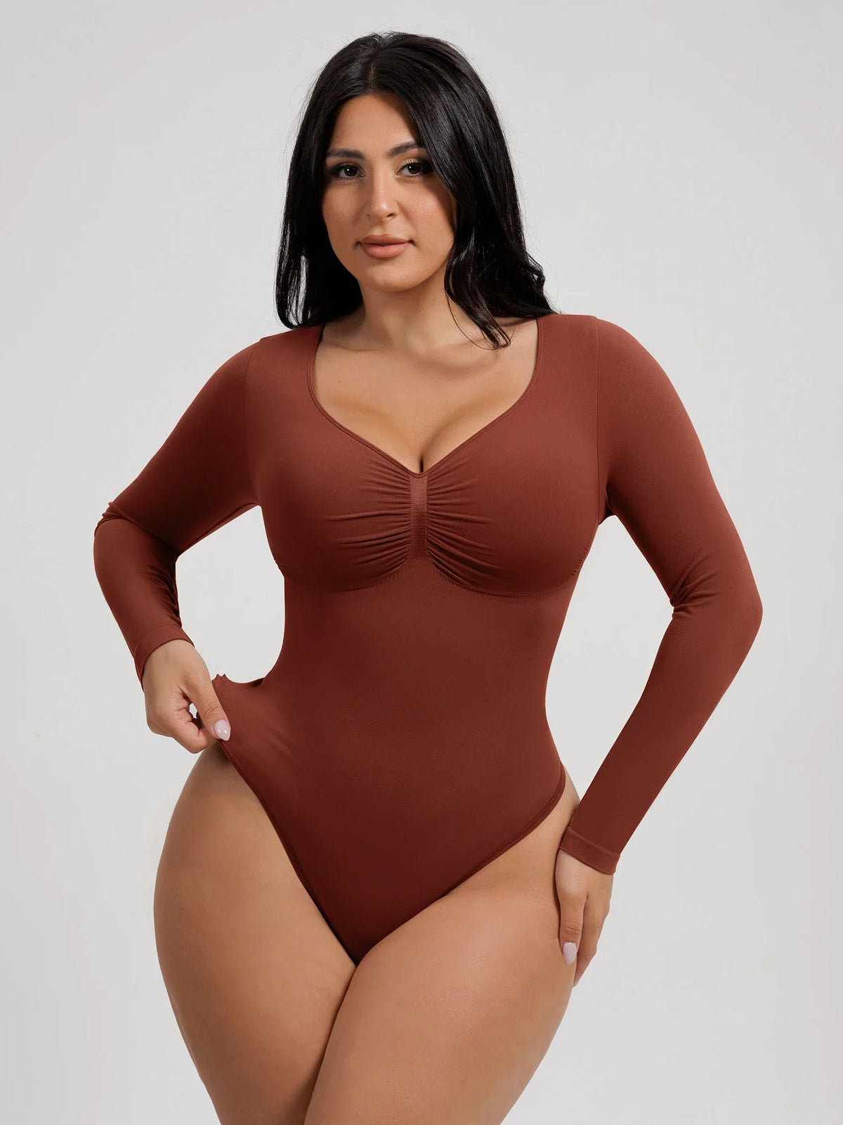 Front view of a model wearing a brown long-sleeve seamless bodysuit with diamond neckline and tummy shaping
